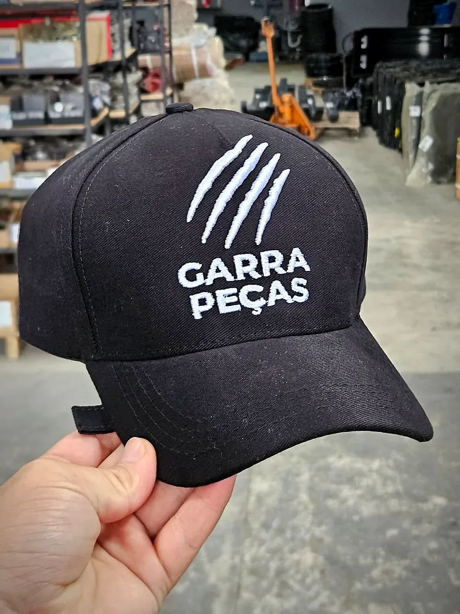 Boné preto com bordado branco, segurado na mão